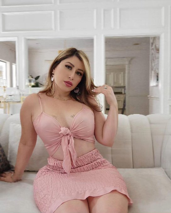 @marleny1 onlyfans model sitting on the couch wearing pink dress