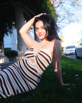 @stellahudgens onlyfans model sitting on the grass wearing stripe dress