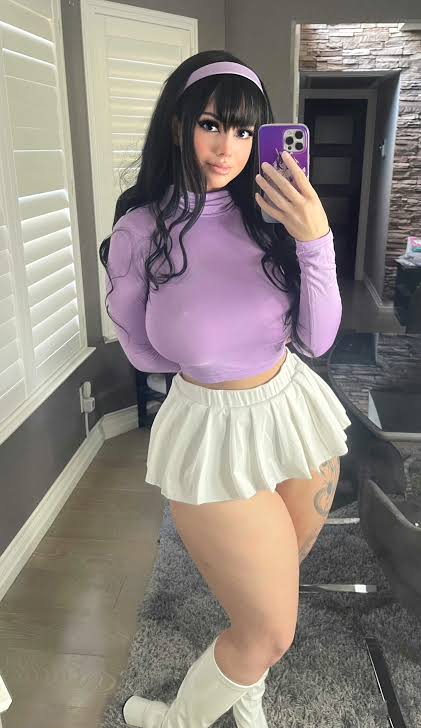 @mimsyheart onlyfans model taking a mirror selfie and wearing purple top and white skirt