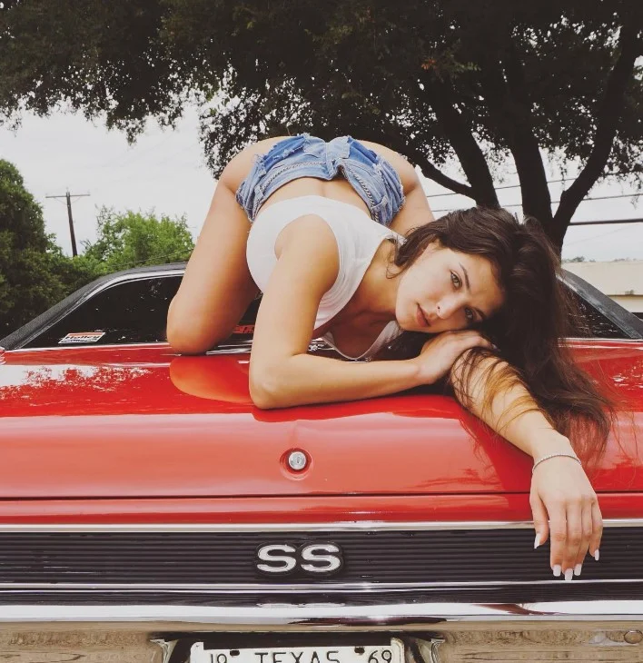 Leah Gotti onlyfans model picture in car wearing denim short and white top