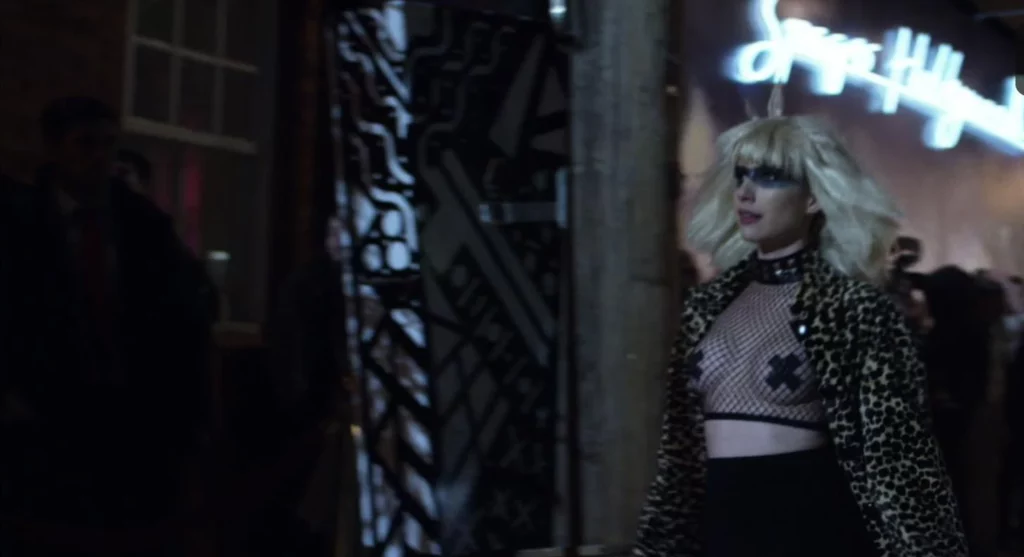 Emma Roberts leaks in the movie Billionaire Boys Club. She is standing wearing see through top