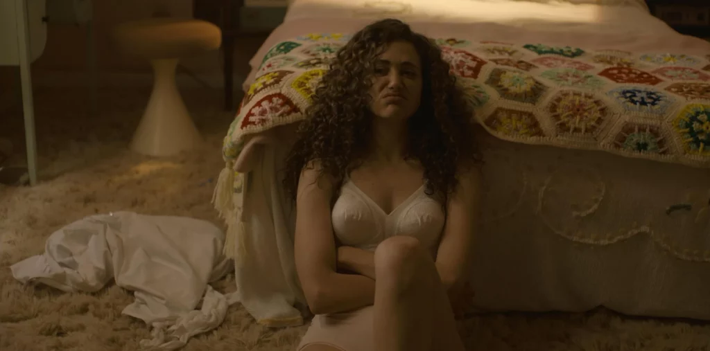Emmy Rossum leaks in the movie The Crowded Room. She is in bedroom wearing white bra