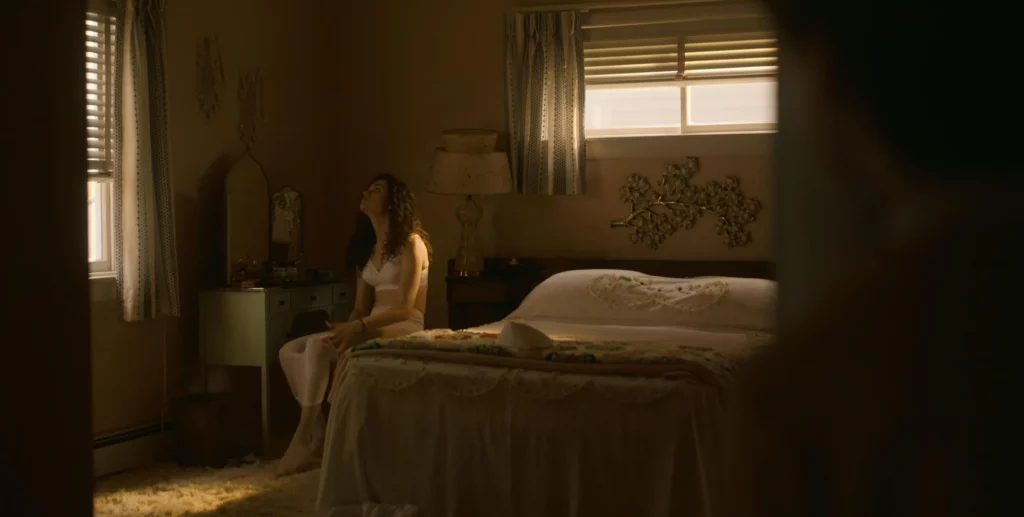 Emmy Rossum leaks in the movie The Crowded Room. She is sitting in the bed wearing white bra
