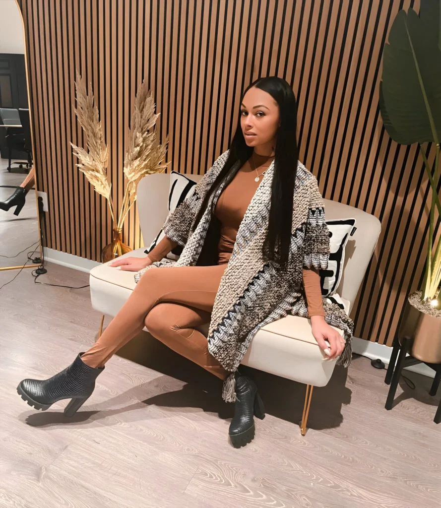 Bethany Benz (@bethanyxxxbenz) OnlyFans model picture sitting on the couch wearing brown suit and black boots